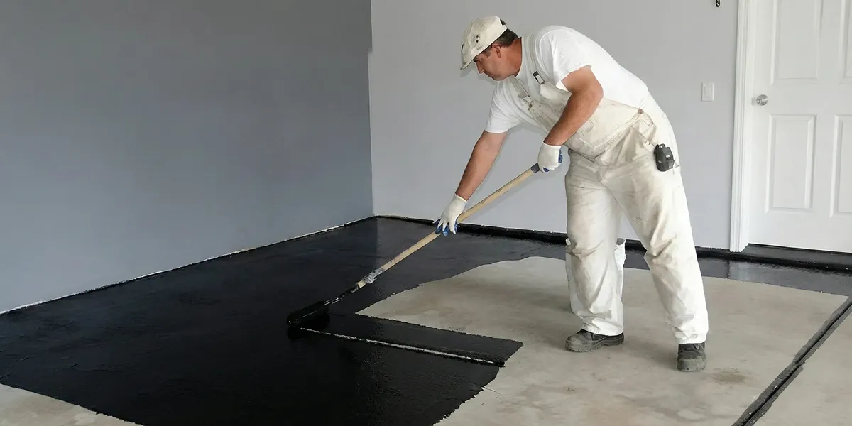 basement waterproofing professional applying waterproof coating to protect a basement floor in Baltimore, MD